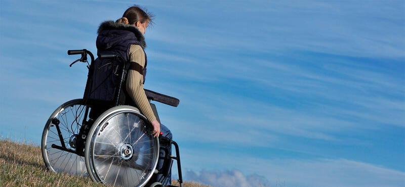 Frau im Rollstuhl vor Himmel